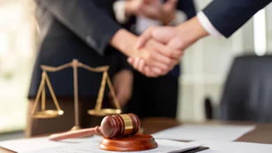 Händeschütteln über einem Schreibtisch mit Richterhammer und Justizwaage.